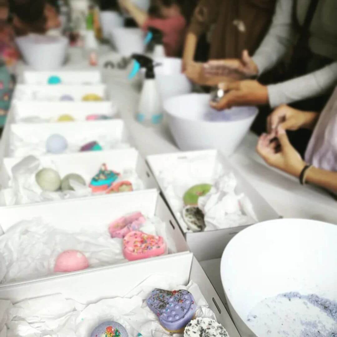 Containers with bath bomb powder and hands making bath bombs